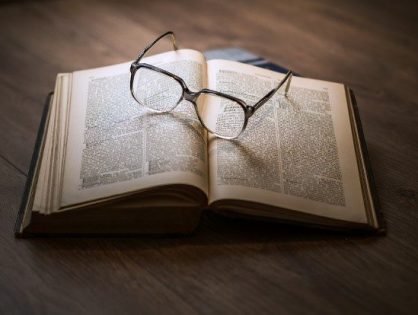 An open book with eye glasses on an open page.